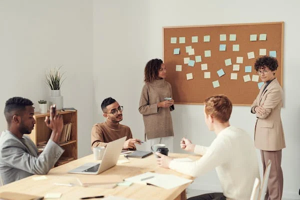 people discussing with a cork board